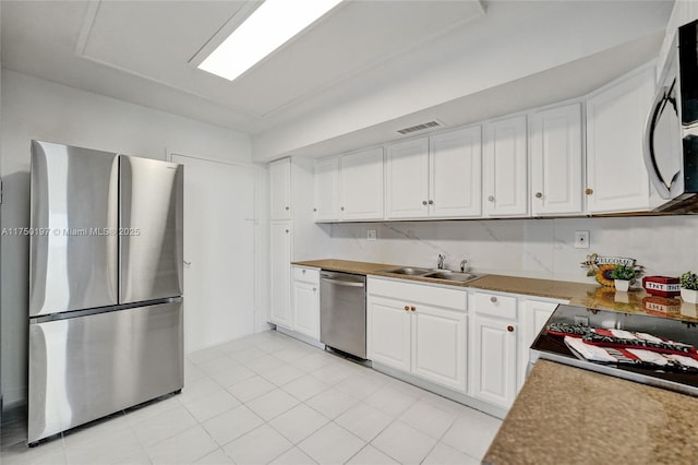 kitchen with stainless steel appliances, light countertops, white cabinetry, and a sink