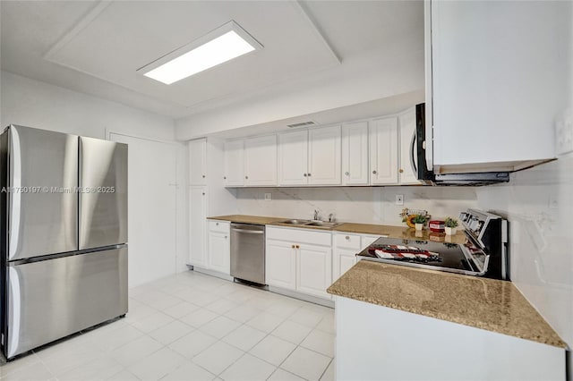 kitchen with stainless steel appliances, a sink, light stone countertops, and white cabinets