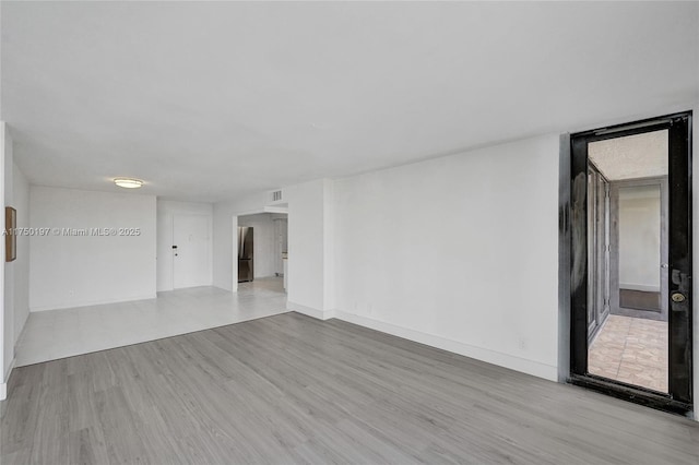 spare room with light wood-style floors and baseboards