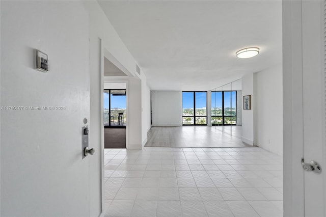 spare room with light tile patterned floors, plenty of natural light, visible vents, and floor to ceiling windows