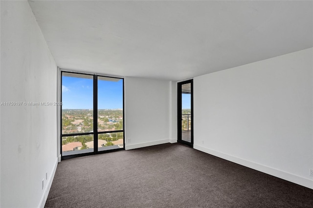 empty room with expansive windows, dark carpet, and baseboards