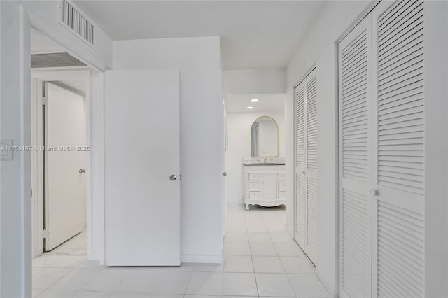 corridor with visible vents, a sink, and light tile patterned flooring