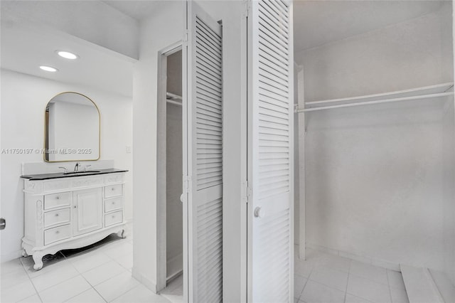 bathroom with a walk in closet, vanity, recessed lighting, and tile patterned floors