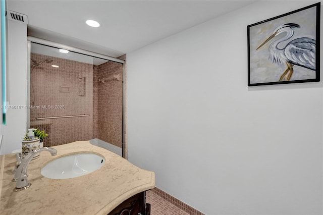 bathroom featuring a shower with door and vanity