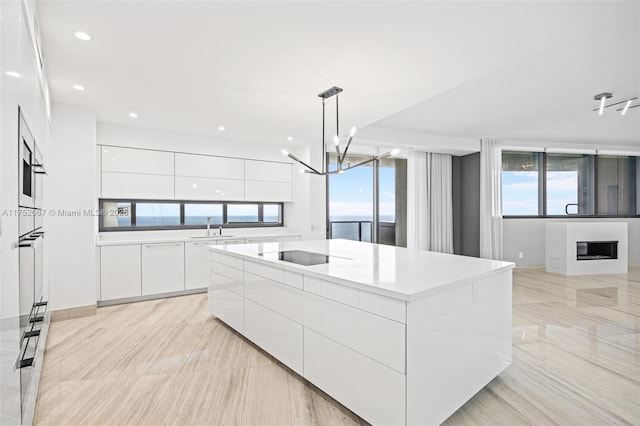 kitchen featuring hanging light fixtures, a large island, modern cabinets, and white cabinets