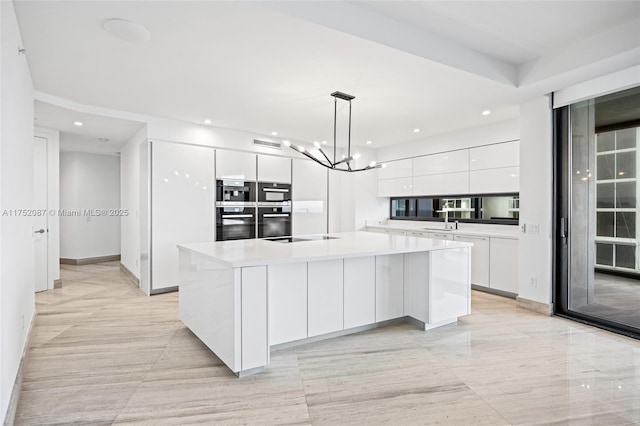 kitchen with white cabinetry, pendant lighting, light countertops, and a center island