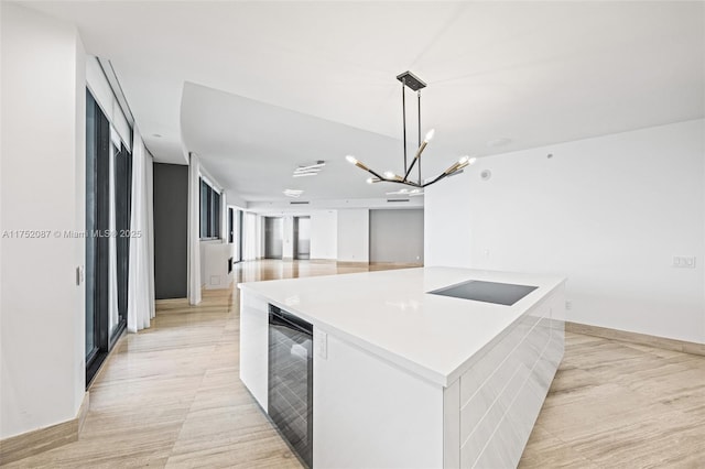 kitchen with beverage cooler, a spacious island, open floor plan, light countertops, and pendant lighting