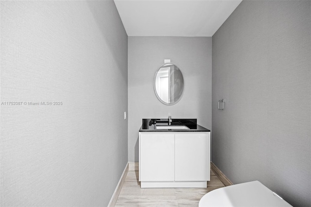 half bathroom featuring toilet, wood finished floors, vanity, and baseboards