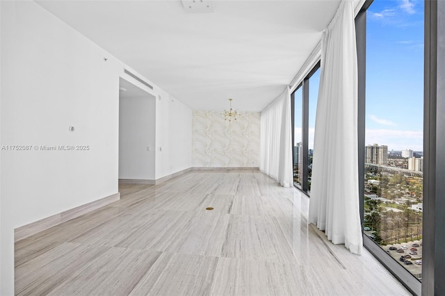 unfurnished room with a wall of windows, a city view, baseboards, and an inviting chandelier