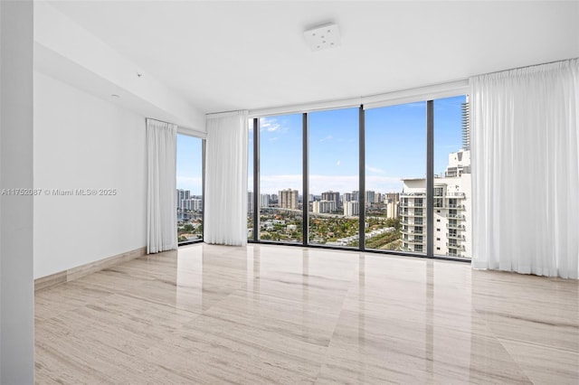 spare room with a view of city, baseboards, and expansive windows