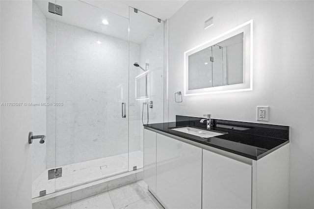 bathroom with marble finish floor, a shower stall, and vanity