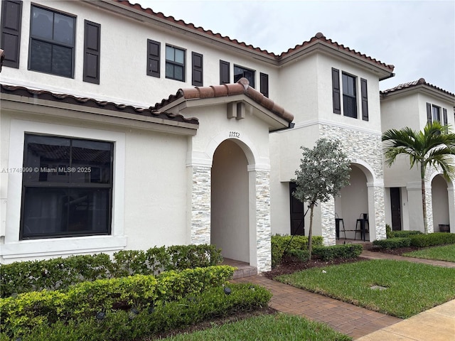 mediterranean / spanish-style house with stone siding and stucco siding