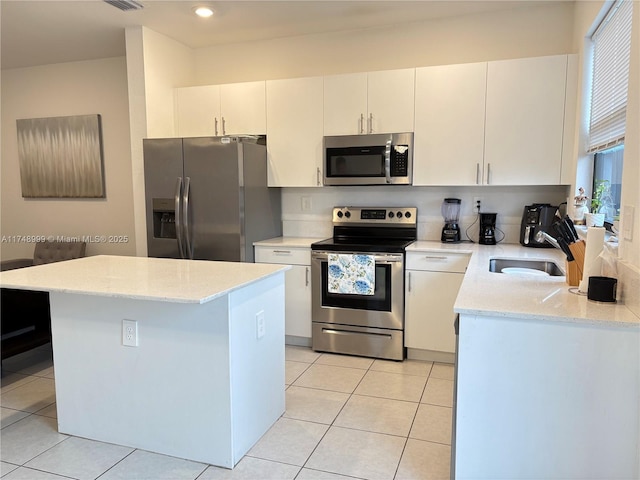 kitchen with a center island, light tile patterned floors, appliances with stainless steel finishes, white cabinetry, and a sink