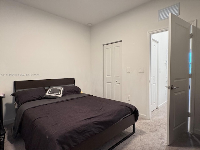 bedroom featuring baseboards, visible vents, a closet, and light colored carpet