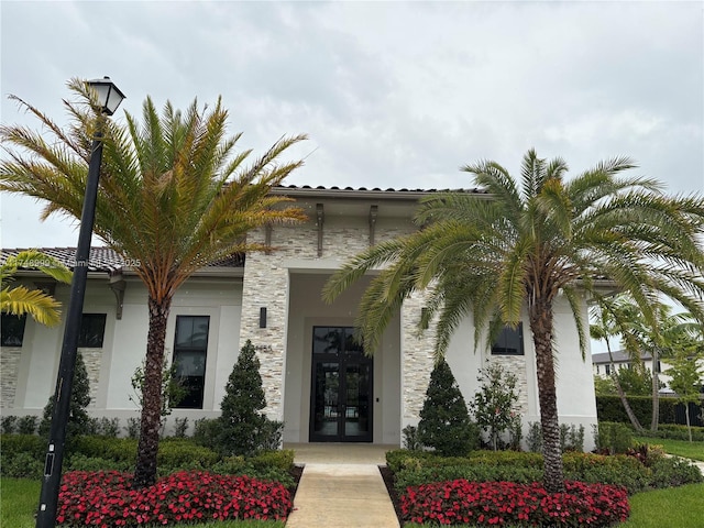 doorway to property featuring stucco siding, stone siding, and french doors