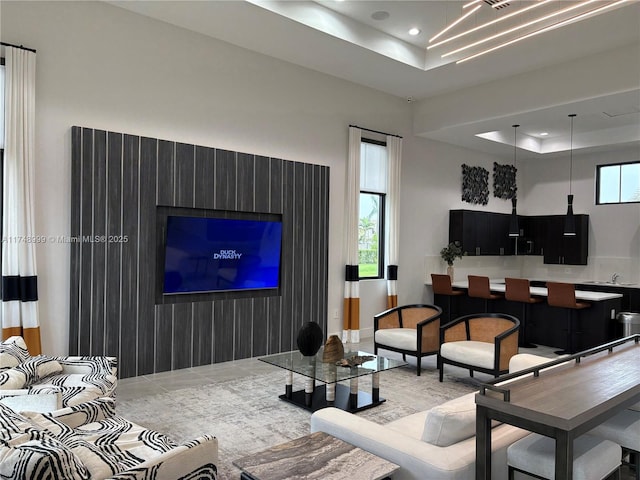 living area featuring a tray ceiling, a wealth of natural light, and recessed lighting