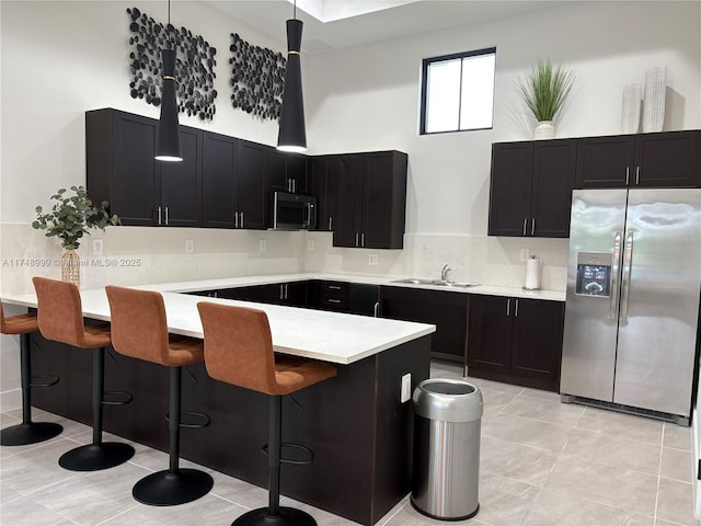 kitchen with decorative backsplash, a breakfast bar area, stainless steel appliances, light countertops, and a sink