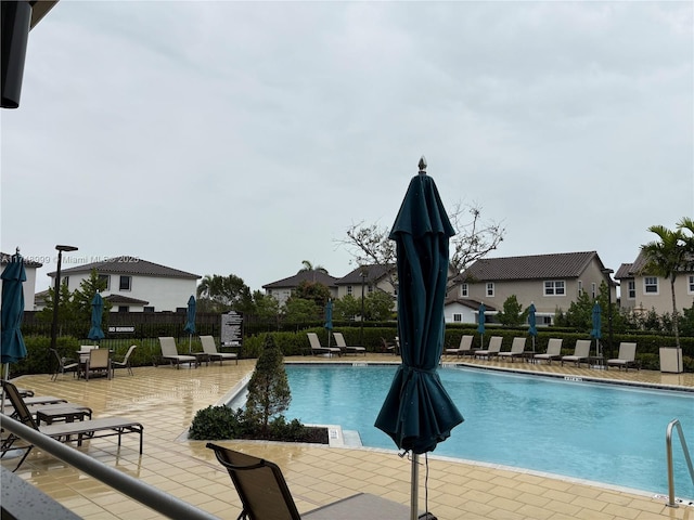 pool with a patio area, a residential view, and fence