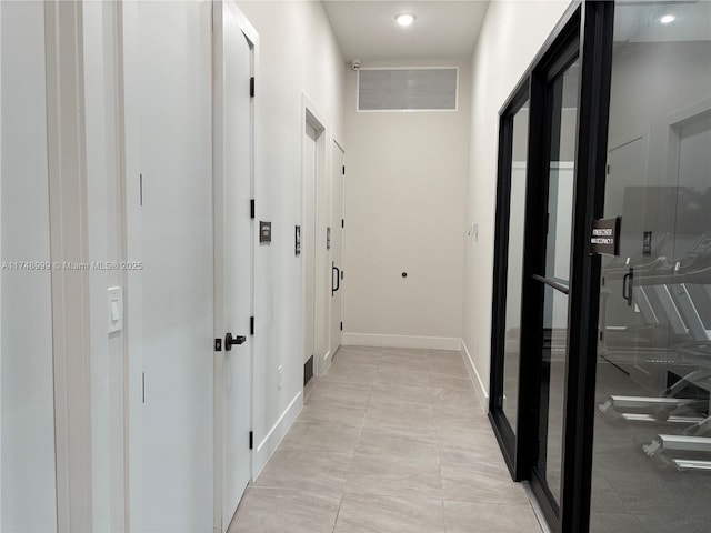 hallway featuring baseboards and visible vents