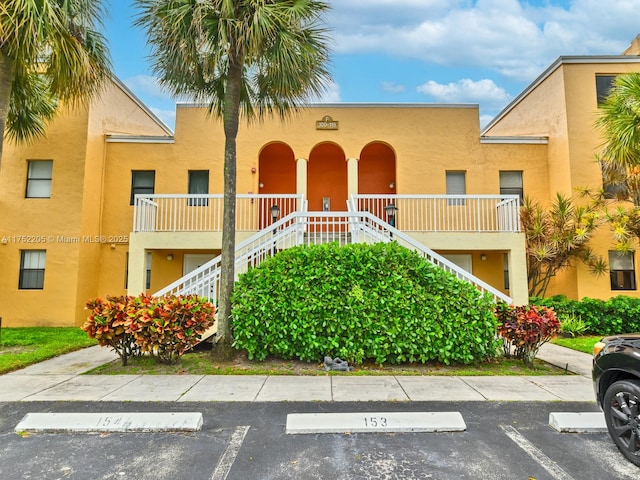 view of property with uncovered parking and stairs