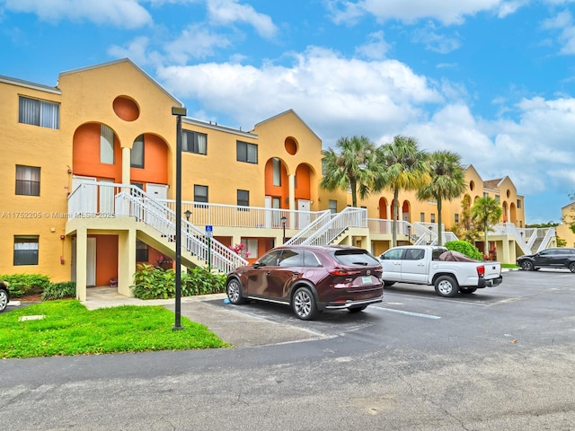 view of building exterior with uncovered parking and stairway