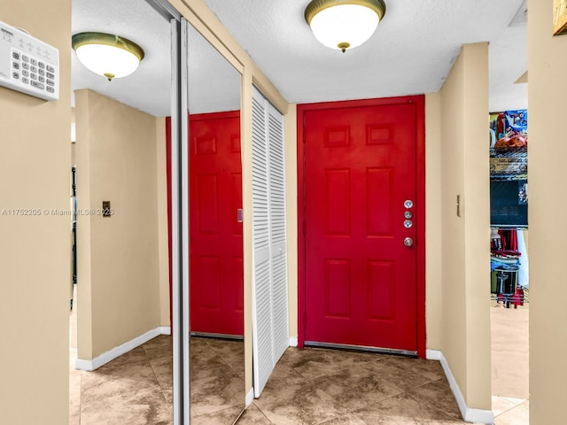 foyer entrance with a textured ceiling and baseboards