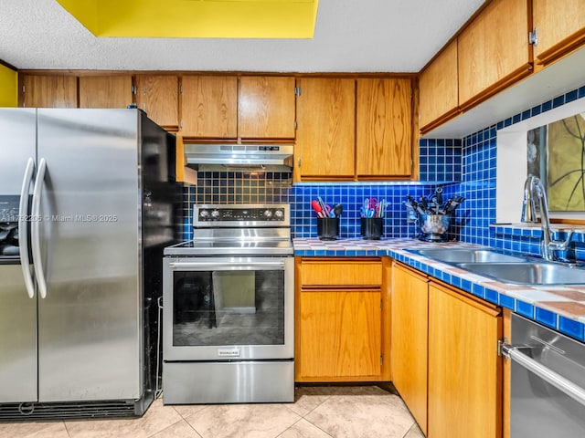 kitchen with stainless steel appliances, decorative backsplash, a sink, and under cabinet range hood