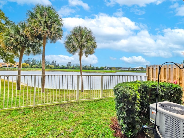 view of yard with central AC unit, a water view, and fence