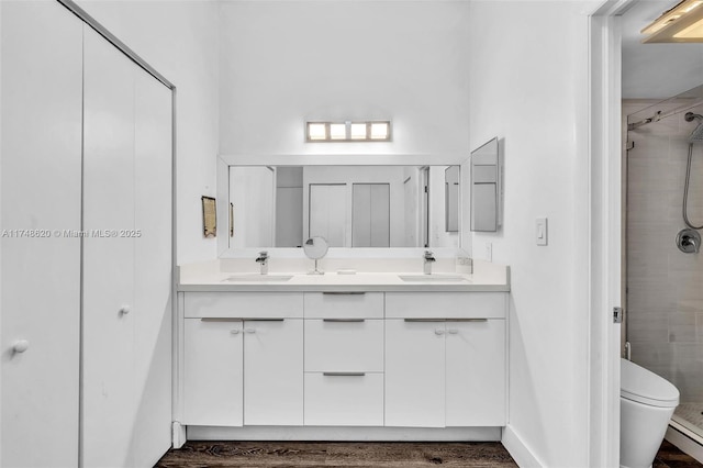 full bathroom with double vanity, a stall shower, toilet, and a sink