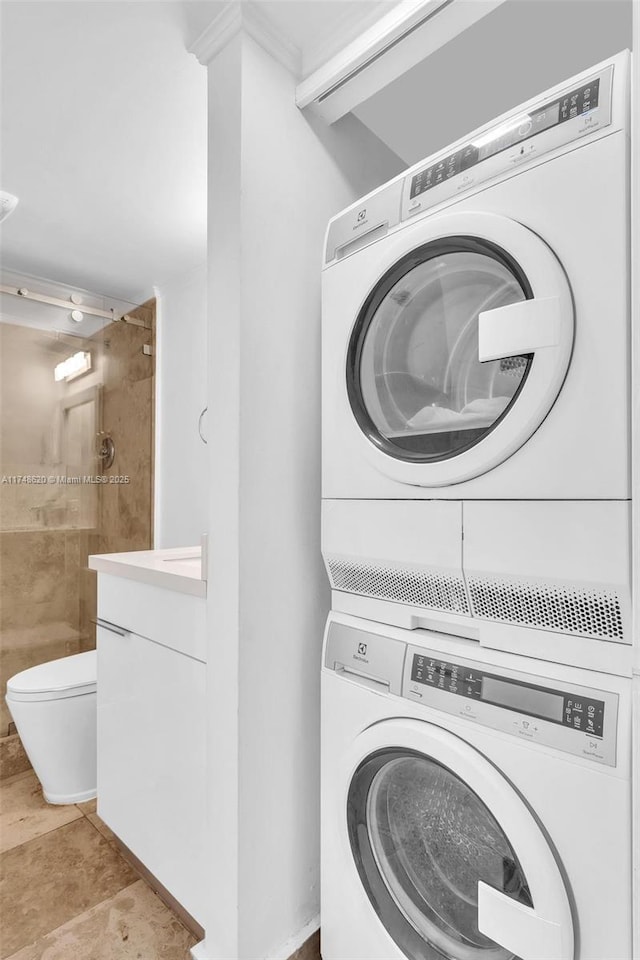 laundry area featuring laundry area, light tile patterned flooring, and stacked washer and clothes dryer