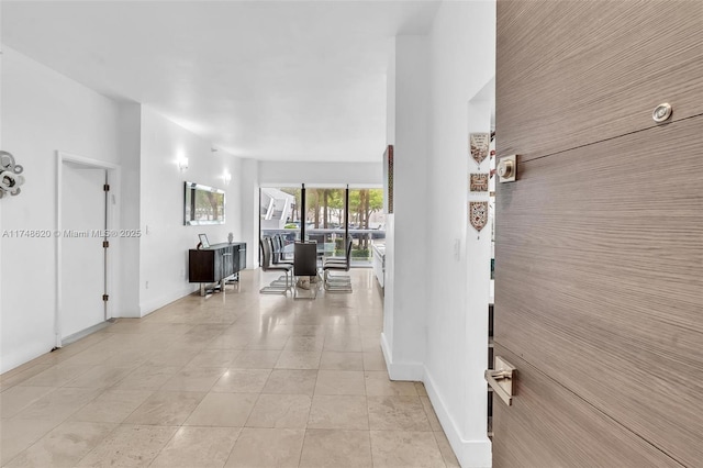 hallway featuring baseboards and light tile patterned floors