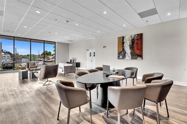 dining room with expansive windows, a paneled ceiling, baseboards, and wood finished floors