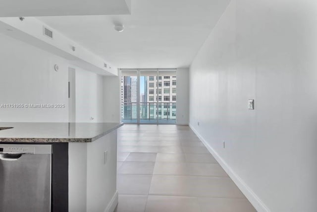 kitchen featuring expansive windows, stainless steel dishwasher, visible vents, and baseboards