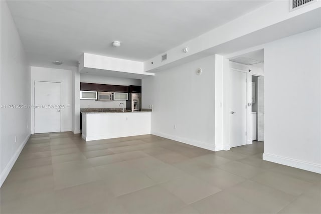 unfurnished living room featuring a sink, visible vents, and baseboards