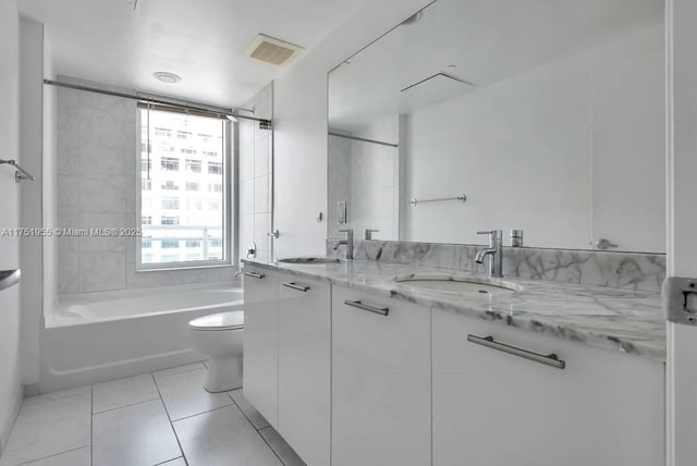 full bathroom with toilet, double vanity, a sink, and visible vents