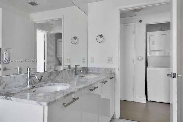 full bath with stacked washer / drying machine, visible vents, and a sink