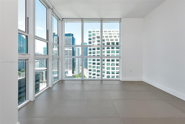 empty room featuring baseboards, floor to ceiling windows, and a city view