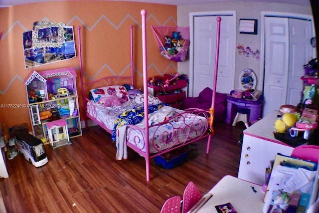 bedroom featuring multiple closets and wood finished floors