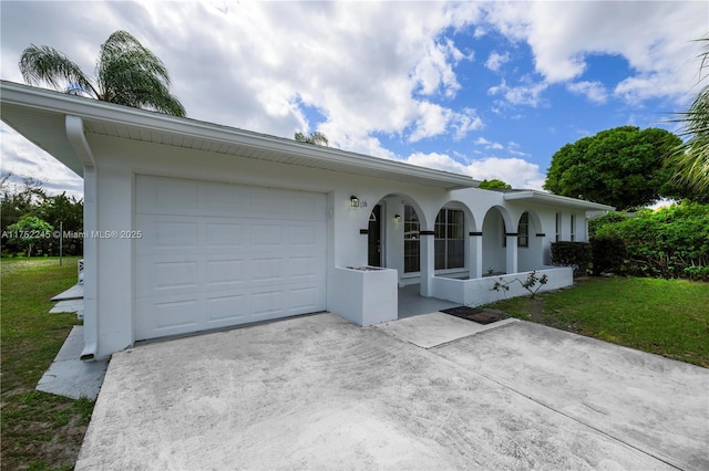 ranch-style home with stucco siding, concrete driveway, covered porch, an attached garage, and a front yard