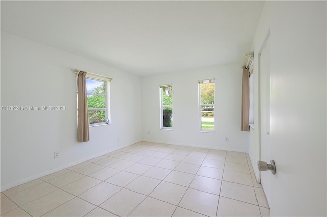 unfurnished room featuring light tile patterned flooring, a wealth of natural light, and baseboards