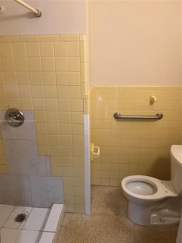 full bathroom featuring a wainscoted wall, tile walls, toilet, a shower stall, and speckled floor