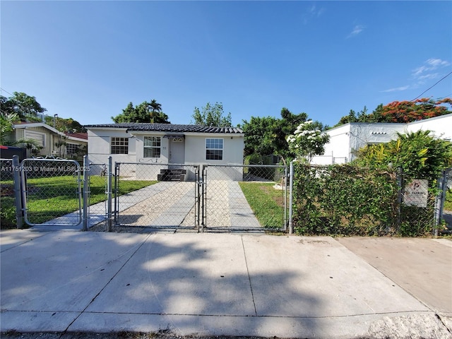 view of front of property with driveway, a fenced front yard, a gate, and stucco siding