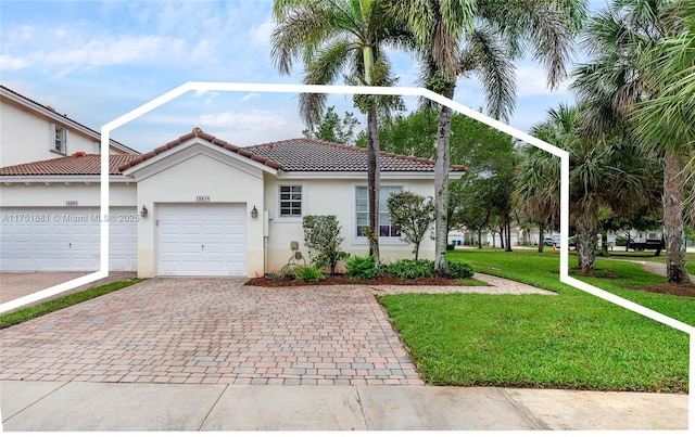 view of front of home featuring decorative driveway, a tile roof, stucco siding, a garage, and a front lawn