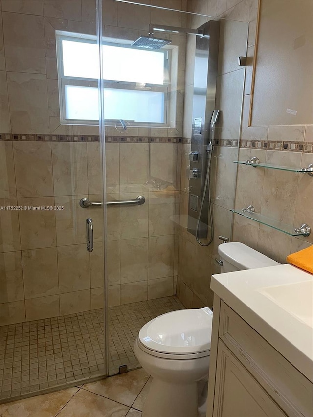 full bath with tile walls, toilet, a shower stall, vanity, and tile patterned flooring