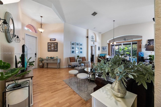 living area featuring high vaulted ceiling, visible vents, ceiling fan, and light wood-style flooring