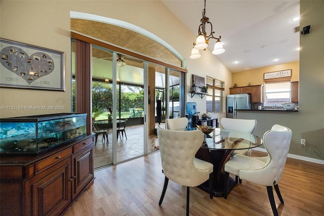 dining area with lofted ceiling, light wood finished floors, plenty of natural light, and an inviting chandelier