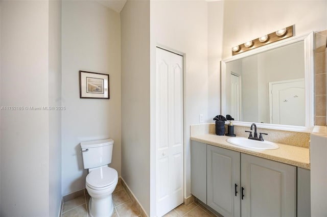 bathroom featuring a closet, toilet, vanity, tile patterned flooring, and baseboards