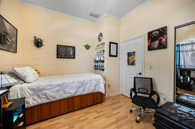 bedroom featuring light wood finished floors, visible vents, and ornamental molding