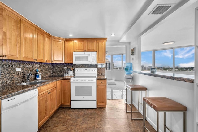 kitchen featuring white appliances, tasteful backsplash, visible vents, and a sink