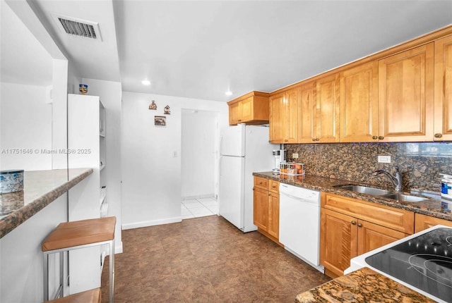 kitchen featuring visible vents, decorative backsplash, a sink, dark stone countertops, and white appliances